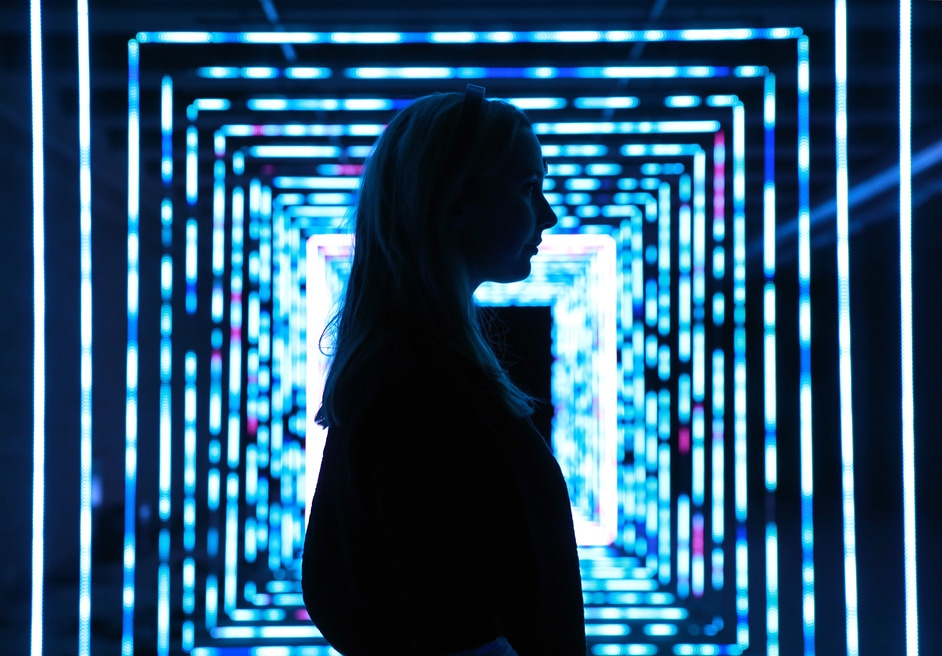 A visitor inside a blue light installation at Illumination